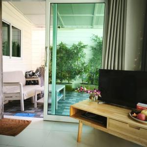 sala de estar con TV y puerta corredera de cristal en Cozy house by the sea, en Ko Pha Ngan