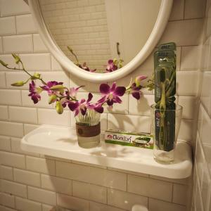 lavabo con jarrón de flores y espejo en Cozy house by the sea, en Ko Pha Ngan