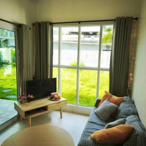 Una sala de estar con un sofá y un televisor y ventanas. en Cozy house by the sea, en Ko Pha Ngan 20 fotos más