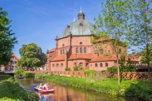 people in a boat on a river in front of a building at NINO-Boardinghouse 16 in Nordhorn