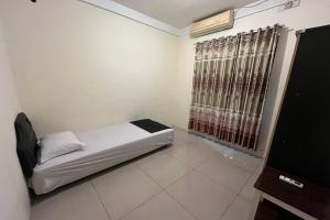 a small bedroom with a bed and a window at Spot on Homestay Griya Sunarti in Yogyakarta