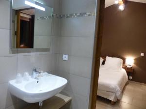 a bathroom with a sink and a bed at Maison d'Hôtes Zella in Bains de Guitera