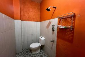 a bathroom with a toilet and an orange wall at Spot on Homestay Griya Sunarti in Yogyakarta +24 photos