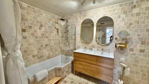 a bathroom with a tub and a sink and mirror at Maison Coup de Cœur in Beaune