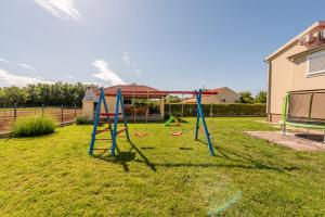 a playground with two swings in a yard at Villa Sami ZadarVillas in Pristeg