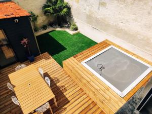 a wooden table and chairs on a patio with a tennis court at Maison de ville au calme in Cognac