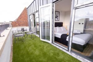 ein Schlafzimmer mit einem Bett und einem Balkon mit grünem Gras in der Unterkunft Brand-New Top-Floor Flat with Stunning Balcony & Parking in Borehamwood