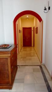 エル・プエルト・デ・サンタマリアにあるカーサ デル レヒドーラの木製のドレッサーと赤いドアが付いたアーチ型の廊下