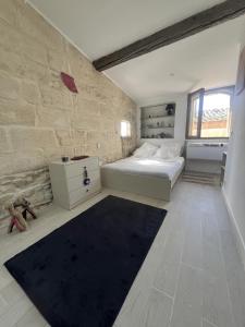a bedroom with a bed and a stone wall at Maison calme et climatisée - Proche Nîmes & Arles in Saint-Gilles