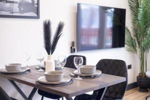 a wooden table with plates and wine glasses on it at Brand-New Borehamwood 1-Bed, 1-Bath Flat in Borehamwood