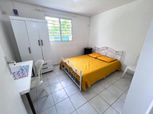 a bedroom with a yellow bed in a white room at Villa plaisir de vivre in Petit-Bourg