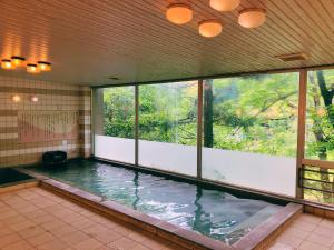 高松市にあるリブマックスリゾート讃岐塩江温泉の窓付きの客室内の大きなスイミングプールを提供しています。