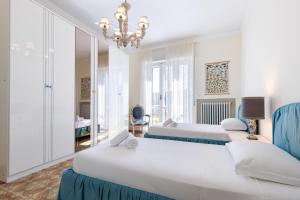 a bedroom with two beds and a chandelier at Hostdomus - Oltremare Suite in Boissano