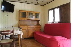 a living room with a red couch and a table at Bungalow al Lago in Ledro