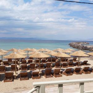 a beach with chairs and umbrellas and the ocean at Marinas house in Vaia