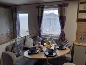 a living room with a table and a couch at Purple Palace 3-Bed Caravan Ingoldmells in Ingoldmells