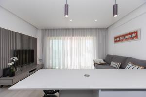 een witte woonkamer met een bank en een tv bij Casa Nau - with pool and sea view in Sesimbra