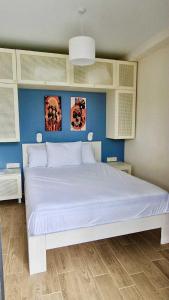 a bedroom with a large white bed with blue walls at Terrace Kapro-one in Itʼkhvisi