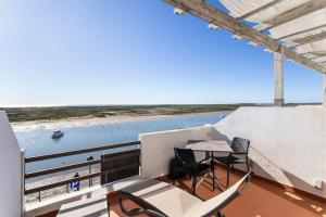 a balcony with a table and chairs and a view of the water at Cabanas de Tavira - Studio in Cabanas de Tavira