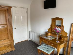 a room with a desk with a mirror and a vase of flowers at Ros Villa Guesthouse in Killarney