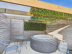 a hot tub on a patio with a table and chairs at Corner House- hot tub and outdoor fireplace in Herstmonceux
