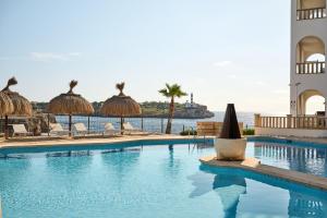 a swimming pool with chairs and umbrellas and the ocean at Orange Colom - Seaside Apartments in Portocolom +105 photos