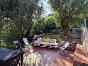 a patio with a bed and two chairs and a tree at Appartamenti vistAmare - La casa del vento in Vibonati