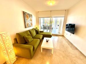 a living room with a green couch and a table at La Cala de Mijas, groundfloor 2 bed apartment steps away from the beach in Mijas Costa