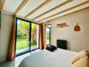 Saint-Côme-de-FresnéにあるLa Maison Rose - Côté Terre by Melroseのベッドと大きな窓のある寝室