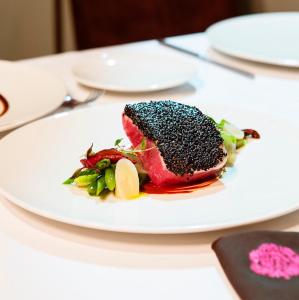 a white plate with a piece of meat on a table at Rosas & Xocolate Boutique Hotel and Spa Merida, a Member of Design Hotels in Mérida +57 photos