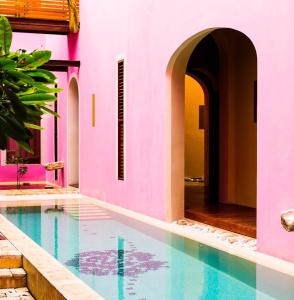 a swimming pool in a house with a pink wall at Rosas & Xocolate Boutique Hotel and Spa Merida, a Member of Design Hotels in Mérida