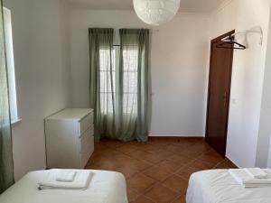 a white room with two beds and a window at Casa Manel in Odemira