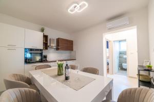 a white kitchen with a dining table and chairs at Apartmani SUNSET in Rab