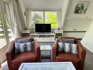 a living room with two chairs and a tv at Chalet Sumo in Durbuy