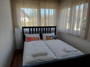 a bed with white sheets and pillows in a room with windows at Villa Sole Apartman Balatonboglár in Balatonboglár +87 photos