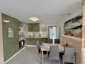 腓特烈港Moderne 2,5 Zimmer-Wohnung的厨房配有绿色橱柜和桌椅