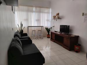 ein Wohnzimmer mit zwei schwarzen Sofas und einem Fernseher in der Unterkunft Penang Tg Bungah Permai Ria Apartment in Tanjung Bungah
