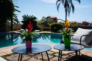 two tables with flowers on them next to a pool at Silvanae Pool Villa in Aci Castello