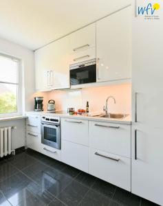 a kitchen with white cabinets and a sink at Ferienhaus Caterlieschen Ferienwohnung 1 in Juist