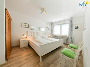 a white bedroom with a bed and a chair at Ferienhaus Caterlieschen Ferienwohnung 1 in Juist