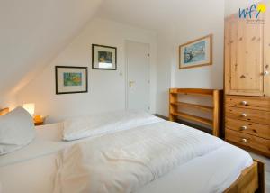 a bedroom with a white bed and a wooden dresser at Ferienhaus Caterlieschen Ferienwohnung 2 in Juist
