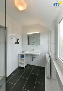a white bathroom with a sink and a mirror at Ferienhaus Caterlieschen Ferienwohnung 2 in Juist +26 photos