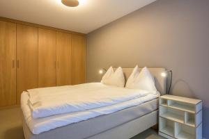a bedroom with a bed with white sheets and wooden cabinets at Edelweiss Ferienwohnung, Stenna Flims in Flims