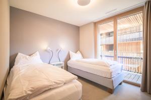 two beds in a room with a window at Edelweiss Ferienwohnung, Stenna Sulegliada in Flims