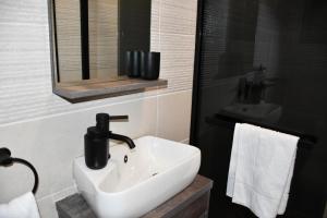 a bathroom with a white sink and a mirror at Setlhoa one bed apartment in Gaborone