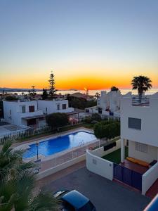 a sunset over a villa with a swimming pool at Apartamento en Marina Beach con vistas al mar in El Pozo del Esparto