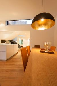 a dining room and kitchen with a wooden table and a large light fixture at Edelweiss La Cerise in Flims