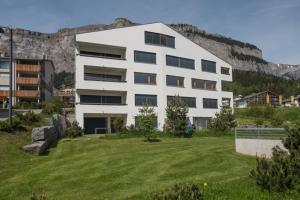 a large white building with a green field in front of it at Edelweiss Casa Cassons in Flims