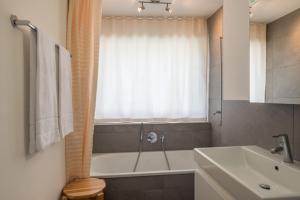 a bathroom with a tub and a sink and a bath tub at Edelweiss Casa Cassons in Flims