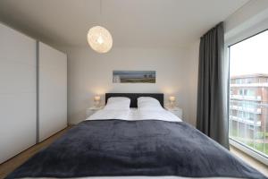 a bedroom with a large bed and a large window at Quartier Hohe Geest 21 in Cuxhaven